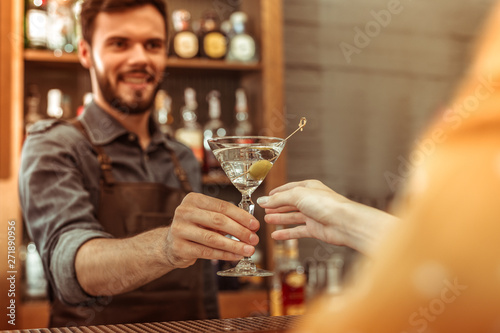 Attractive bar worker handing a martini cocktail to a customer