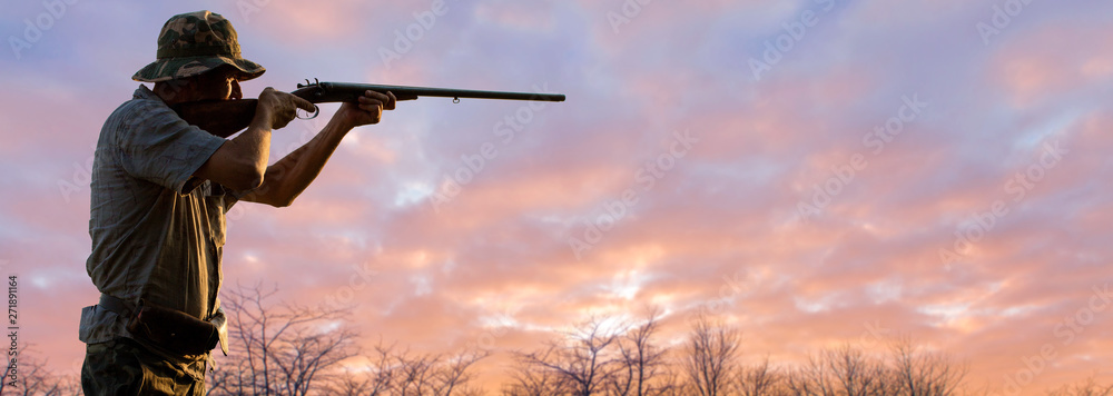 Silhouette of a hunter with a gun in the reeds against the sun, an ambush for ducks with dogs Silhouette of a hunter with a gun in the reeds against the sun, an ambush for ducks with dogs