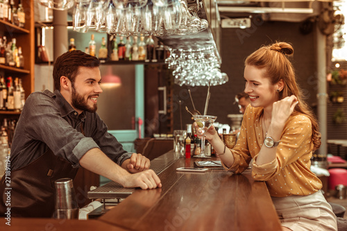 Фотография Red-haired woman talking to bartender while holding a cocktail