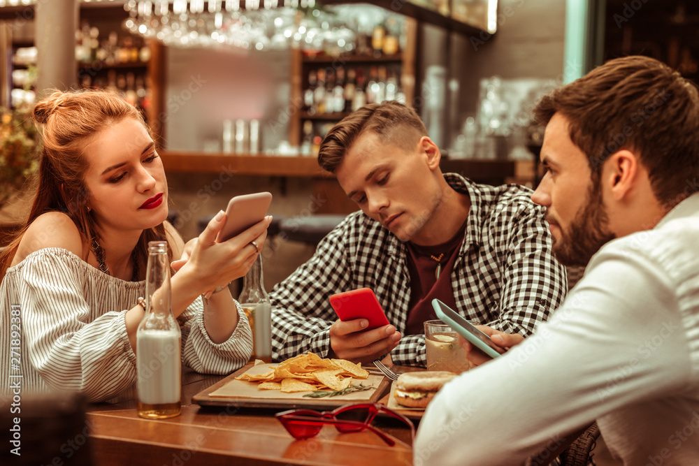 Bored group of three friends being glued to their phones