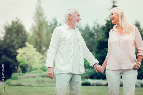 Delighted cheerful man holding his wifes hand