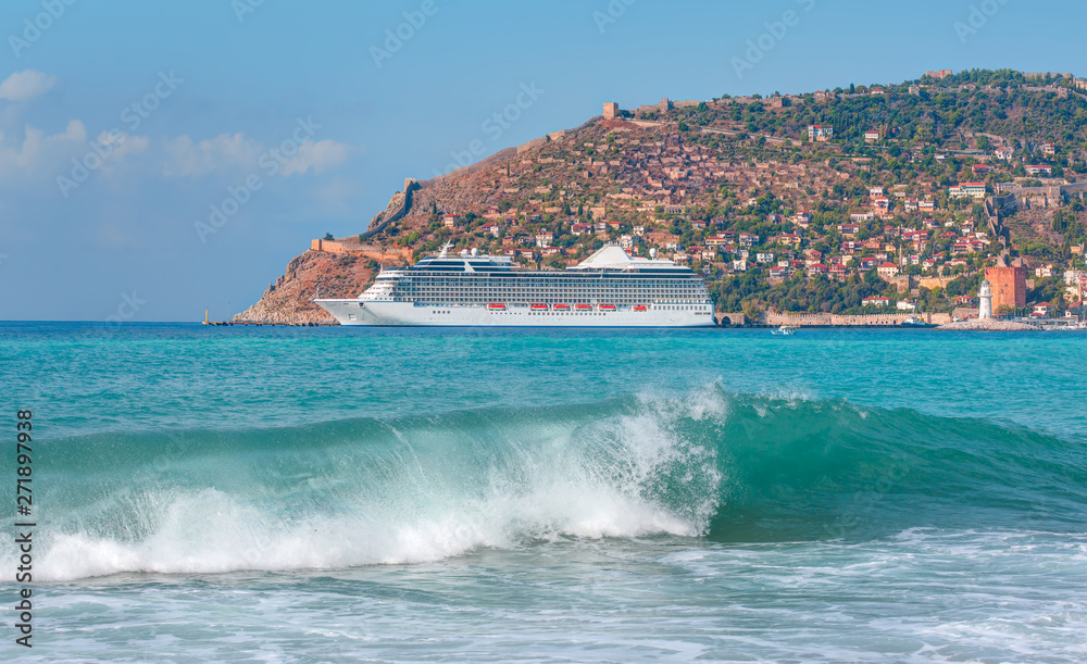 White giant luxury cruise ship on stay at Alanya harbor on the foreground powerfull turquoise wave - Alanya, Turkey