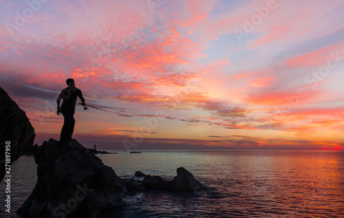 Silhouette of fisherman on the rock at amazing sea sunset © muratart