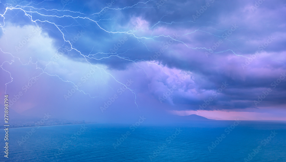 Calm tropical blue sea under amazing storm clouds with lightning 
