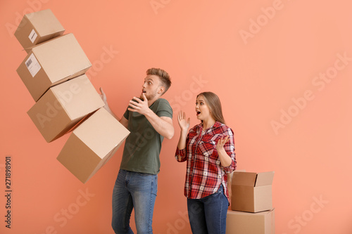 Young couple dropping cardboard boxes on color background