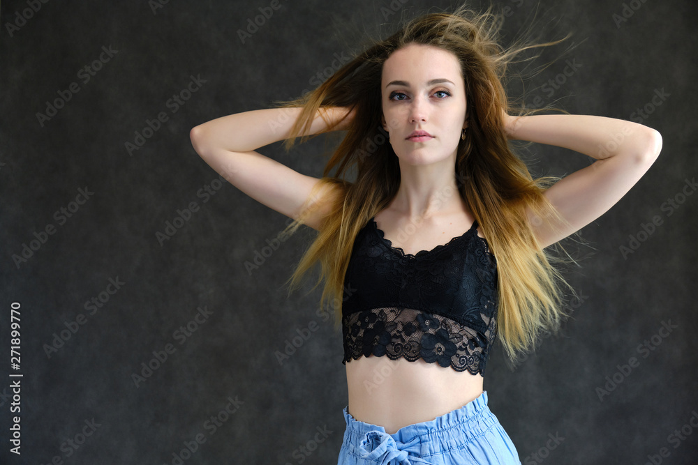 Photograph of a portrait of a beautiful girl woman with long dark flowing hair, happy life on a dark gray background. She is standing directly in front of the camera in various poses and smiling.