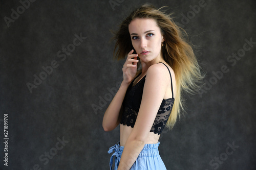 Photograph of a portrait of a beautiful girl woman with long dark flowing hair, happy life on a dark gray background. She is standing directly in front of the camera in various poses and smiling. © Вячеслав Чичаев