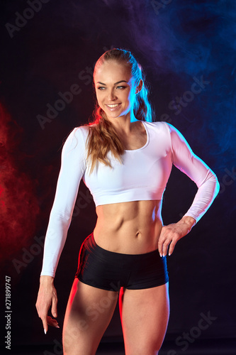 happy slim athlete with long fair hair taking part in a competition. isolated black background with red and blue smoke