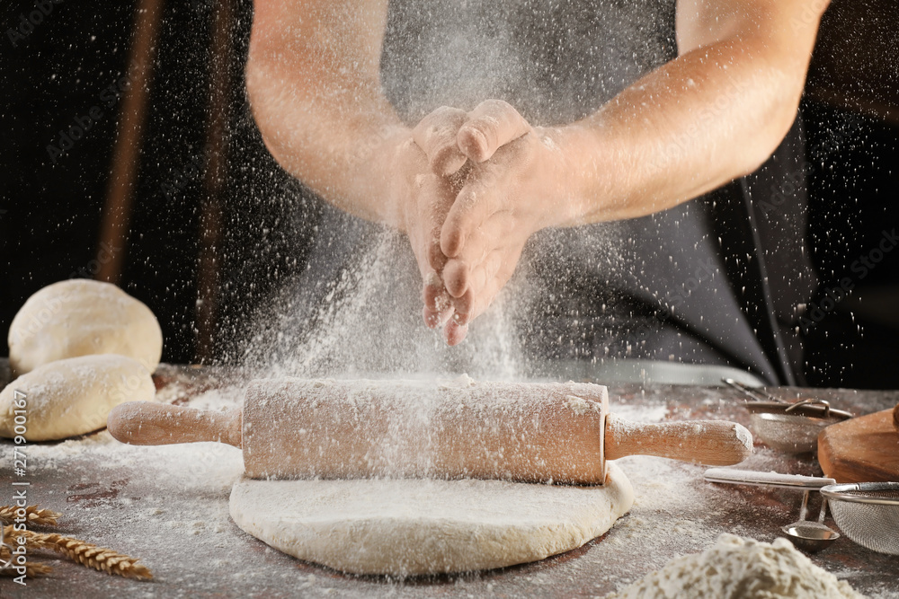 Man clapping hands and sprinkling flour over dough on table Stock Photo ...