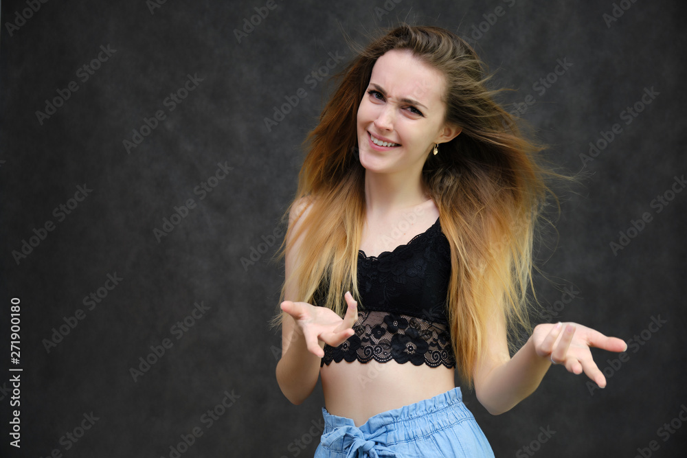 Photograph of a portrait of a beautiful girl woman with long dark flowing hair, happy life on a dark gray background. She is standing directly in front of the camera in various poses and smiling.