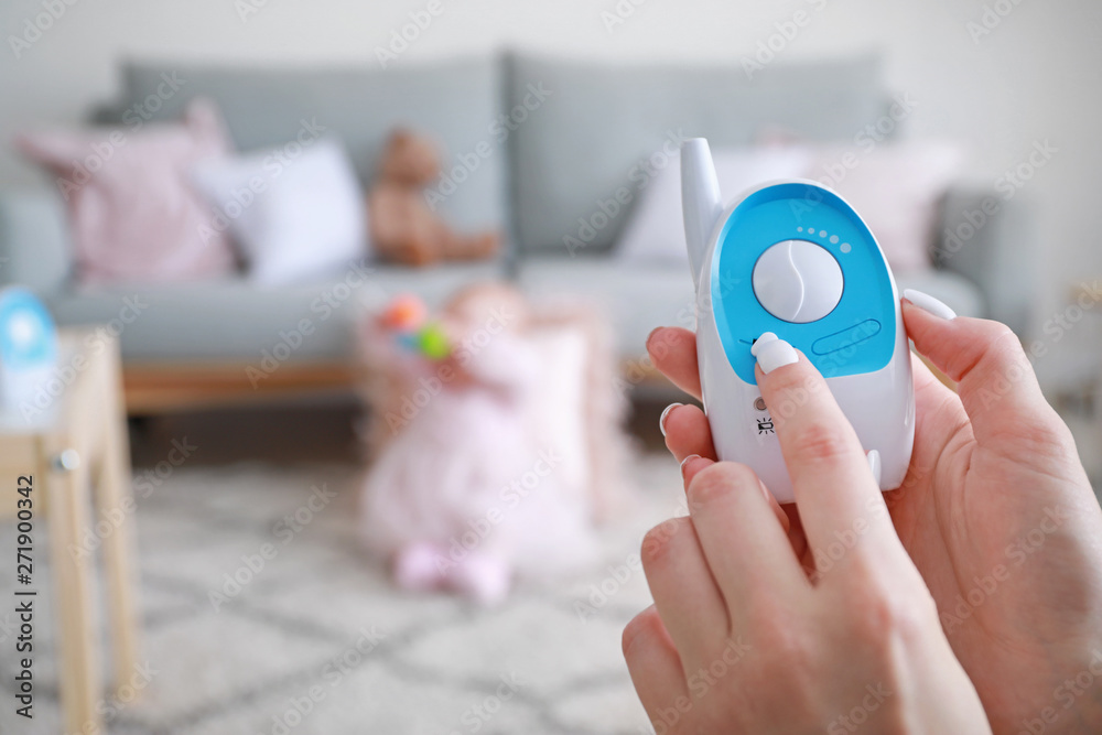 Female hands with modern baby monitor and little child on background Female hands with modern baby monitor and little child on background