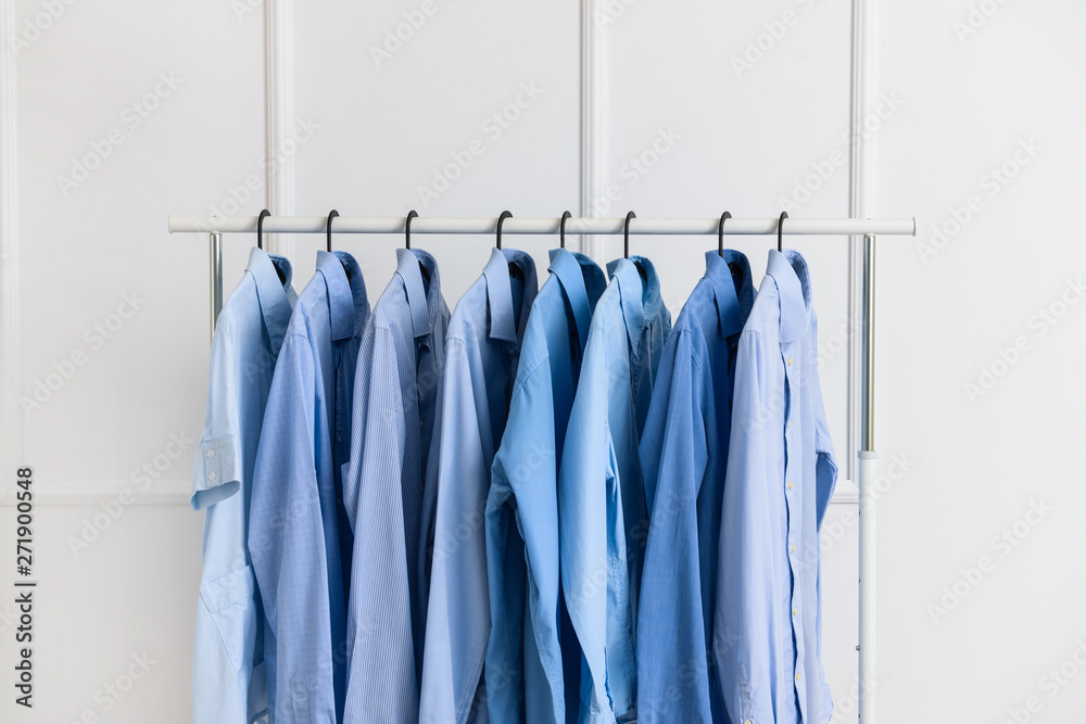 Rack with clothes after dry-cleaning near white wall