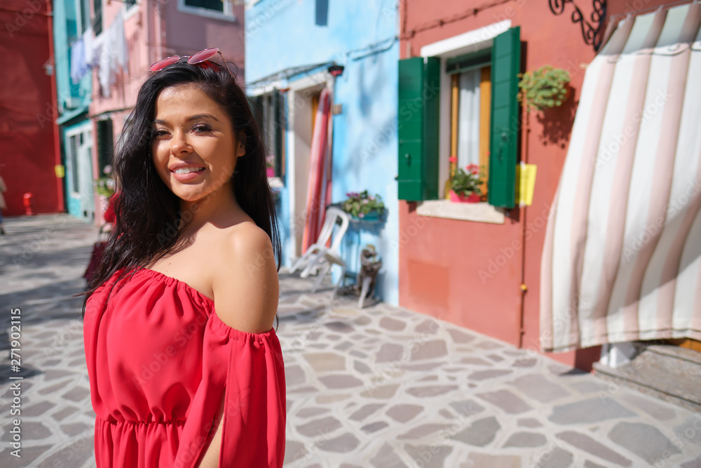 young happy traveler woman posing among colorful houses on Burano island, Venice. Tourism in Italy concept