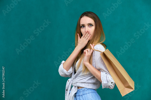 Photograph of a portrait of a beautiful girl woman with long dark flowing hair, loves shopping, on a green background with packages from the store. She is standing in different poses and smiling.