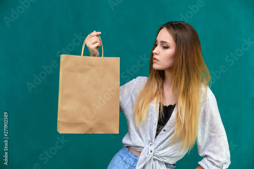 Photograph of a portrait of a beautiful girl woman with long dark flowing hair, loves shopping, on a green background with packages from the store. She is standing in different poses and smiling. © Вячеслав Чичаев