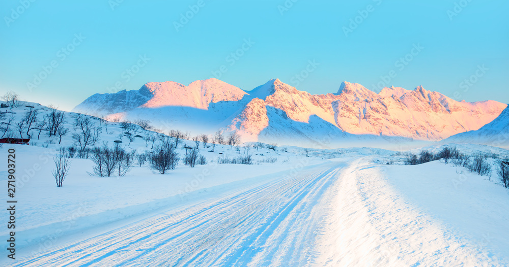 Beautiful winter landscape with snow and ice covered road on the background snowy mountains - Arctic landscape - Snow storm on the empty road - Snow covered road on a winter day - Tromso, Norway Beautiful winter landscape with snow and ice covered road on the background snowy mountains - Arctic landscape - Snow storm on the empty road - Snow covered road on a winter day - Tromso, Norway