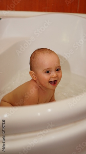 Funny little child playing with water in a bathroom. Toddlers bathes.
