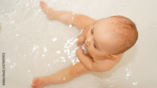 Funny little child playing with water and foam in a bathroom. Toddlers bathes.