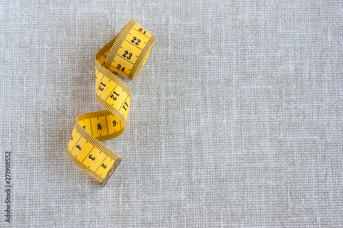 yellow sartorial centimeter tape on a light gray linen background close-up