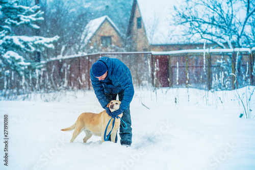 Man and dog are best friends. A man with a dog walks in a village in a snowy winter