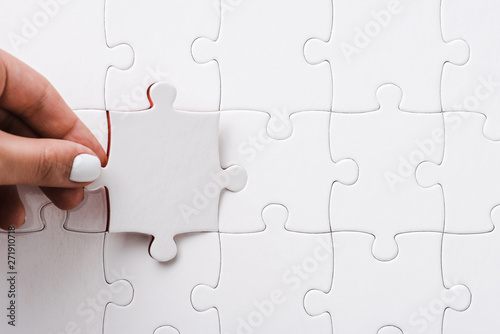 top view of woman holding white jigsaw near connected puzzle pieces photo