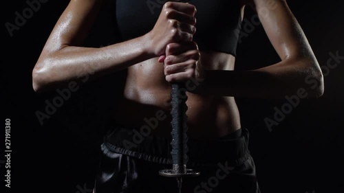 tanned strong girl holding a katana in her hands close-up bellicose pose of the winner dramatically lowers her hands down
