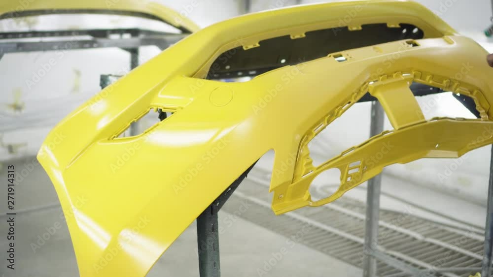 Man with protective clothes and mask painting car using spray compressor ,yellow front bumper Man with protective clothes and mask painting car using spray compressor ,yellow front bumper