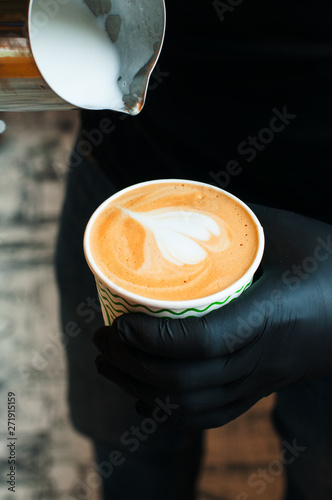 Barista pouring milk in coffee cup. Coffee art.