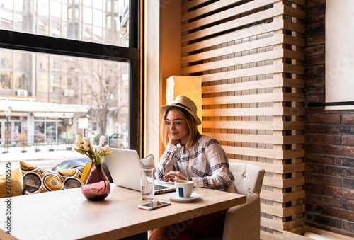 Portrait of young woman using laptop at cafe, she is working on laptop computer at a coffee shop.