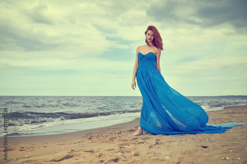 Woman in a blue dress on the beach. Summer woman in a blue dress on the beach Woman in a blue dress on the beach. Summer woman in a blue dress on the beach