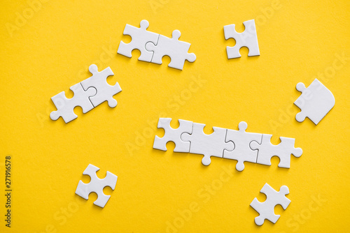 top view of connected and unfinished puzzle pieces isolated on yellow
