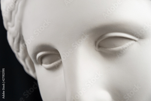 White gypsum copy of ancient statue Venus head on a black background. Plaster sculpture woman face.