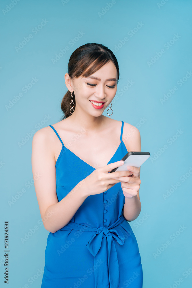 Attractive woman using text messaging feature on her portable device in studio Attractive woman using text messaging feature on her portable device in studio