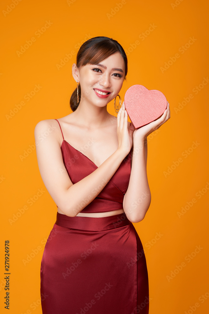 Beautiful woman with heart shaped box on color background.