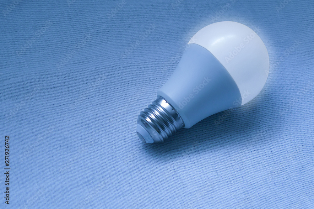 LED bulb lamp closeup image. Blue concept poster of electricity, technologies, money saving and environment friendly utilities. Diode equipment is illuminated with glow and shadows LED bulb lamp closeup image. Blue concept poster of electricity, technologies, money saving and environment friendly utilities. Diode equipment is illuminated with glow and shadows