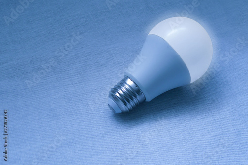 LED bulb lamp closeup image. Blue concept poster of electricity, technologies, money saving and environment friendly utilities. Diode equipment is illuminated with glow and shadows