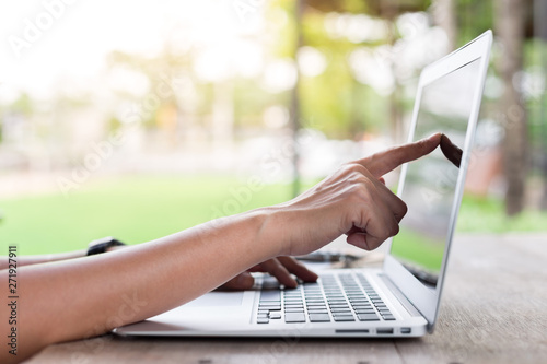 Fototapeta Naklejka Na Ścianę i Meble -  Woman hand pointing at a laptop screen with warm light