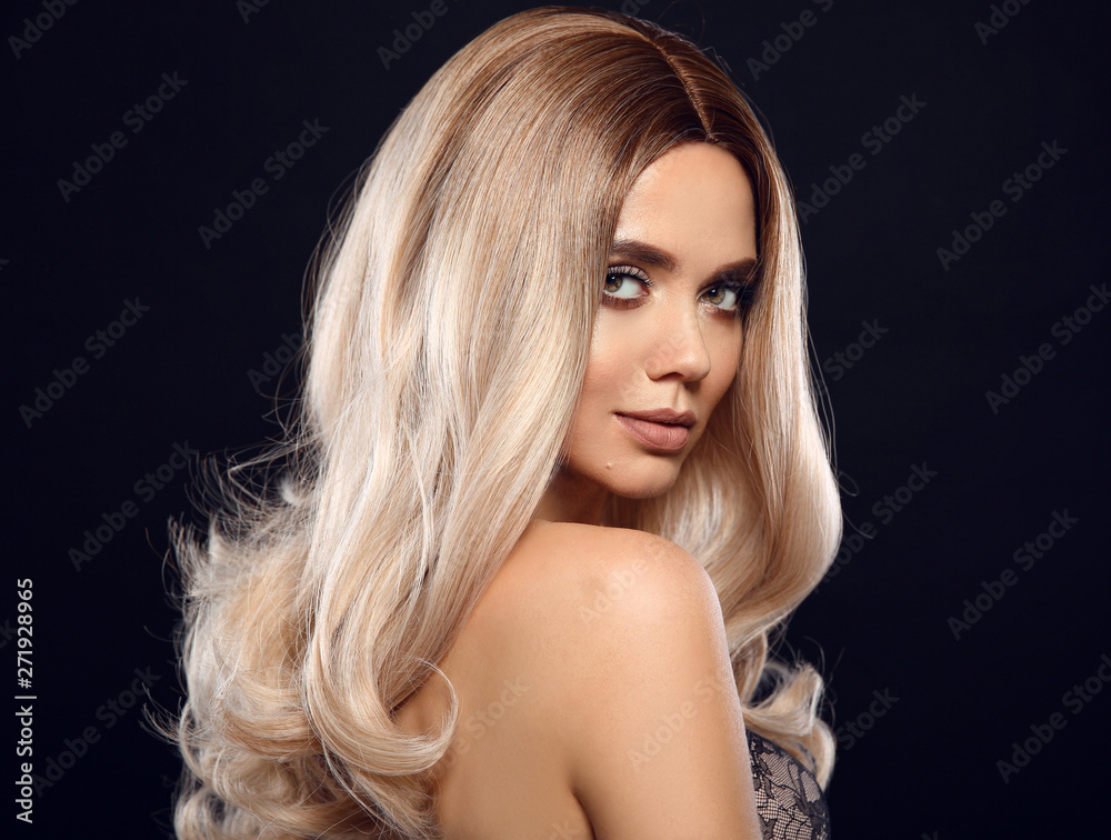 Ombre blond curly hair. Beauty fashion blonde woman portrait. Beautiful girl model with makeup, long healthy hairstyle posing isolated on studio black background. Ombre blond curly hair. Beauty fashion blonde woman portrait. Beautiful girl model with makeup, long healthy hairstyle posing isolated on studio black background.
