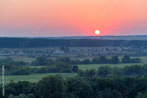 Sun rises in the early morning over the fields and forests