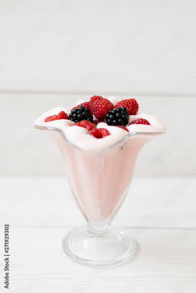 Beautiful pink raspberry snack fruit smoothie or milkshake in a glass with raspberries and blackberries on a white plank . Yogurt cocktail. Natural detoxification. Liquid ice cream. Beautiful pink raspberry snack fruit smoothie or milkshake in a glass with raspberries and blackberries on a white plank . Yogurt cocktail. Natural detoxification. Liquid ice cream.