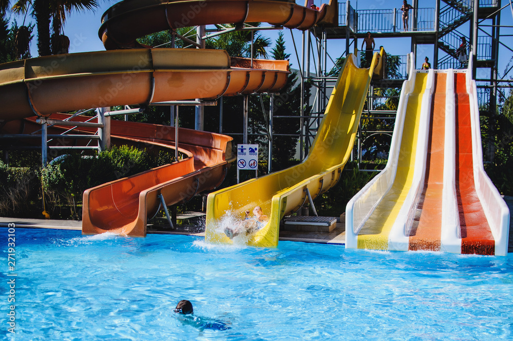 Happy young woman falling into water. sitting in tube on hill. Roll with a water  slide