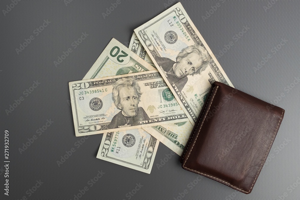 Dollar bills on gray background. Men's leather wallet with dollar bills. Dollar bills on gray background. Men's leather wallet with dollar bills.