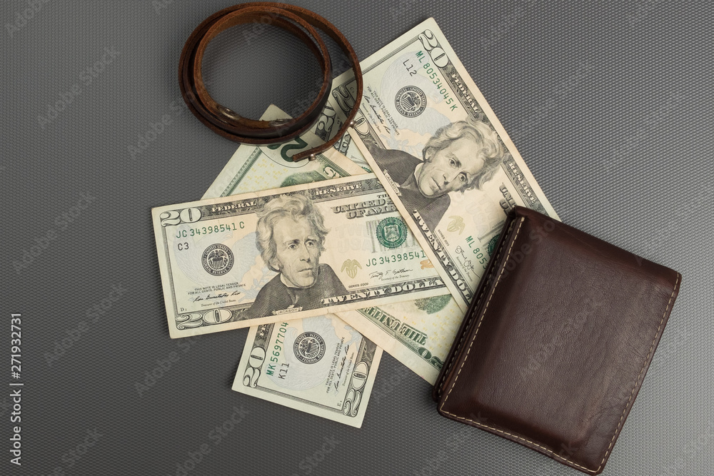 Dollar bills on gray background. Men's leather wallet with dollar bills. Leather bracelet casual.