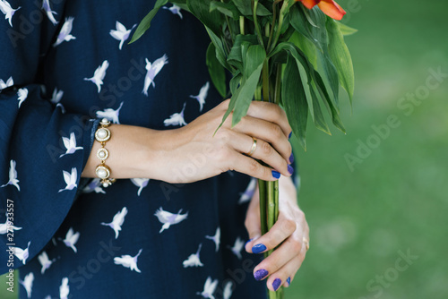 Hands of a married girl who holds a bouquet of flowers. Wedding ring on his hand. Manicure in blue and purple colors