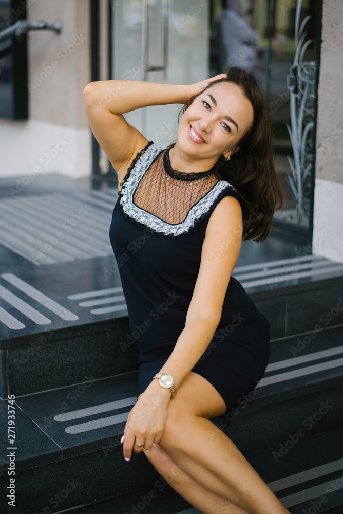 Brunette is sitting on the marble steps, smiling and happy. The concept of the joyful life of a woman of middle age Brunette is sitting on the marble steps, smiling and happy. The concept of the joyful life of a woman of middle age