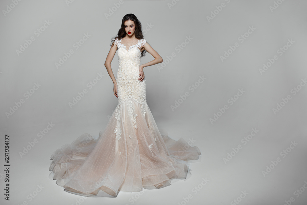 Beauty girl with curly long hair in white wedding dress with embroidery, isolated on a white background.