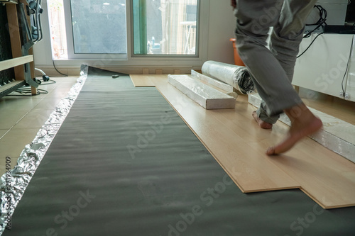 Laminated parquet floor being installed over ceramic tiles.
