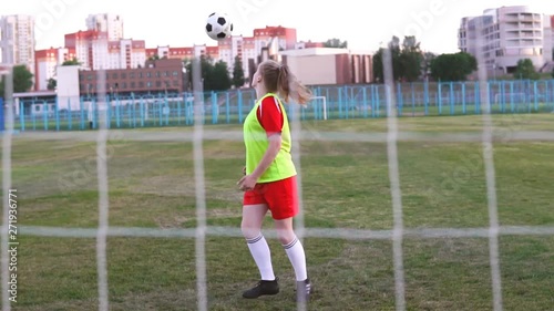 Teen girl football player tricking with the soccer ball in slow motion photo