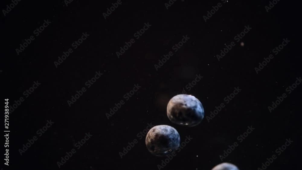 Slow motion of blueberries falling into water against black background. Slow motion of blueberries falling into water against black background.