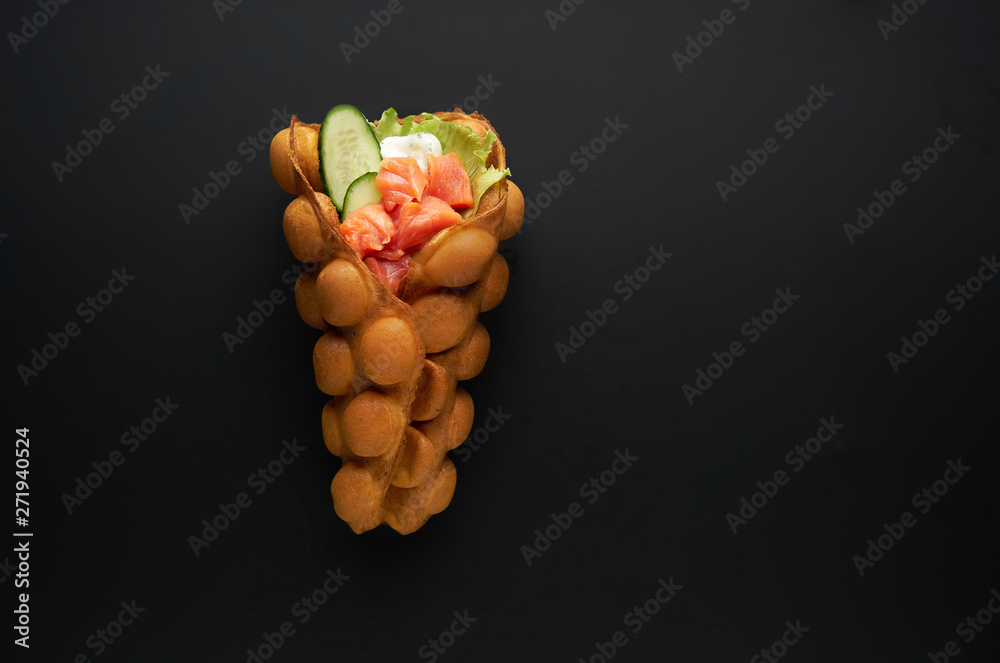 Hong kong or bubble waffle with fresh salmon and sauce on dark bakground. Street food concept Hong kong or bubble waffle with fresh salmon and sauce on dark bakground. Street food concept